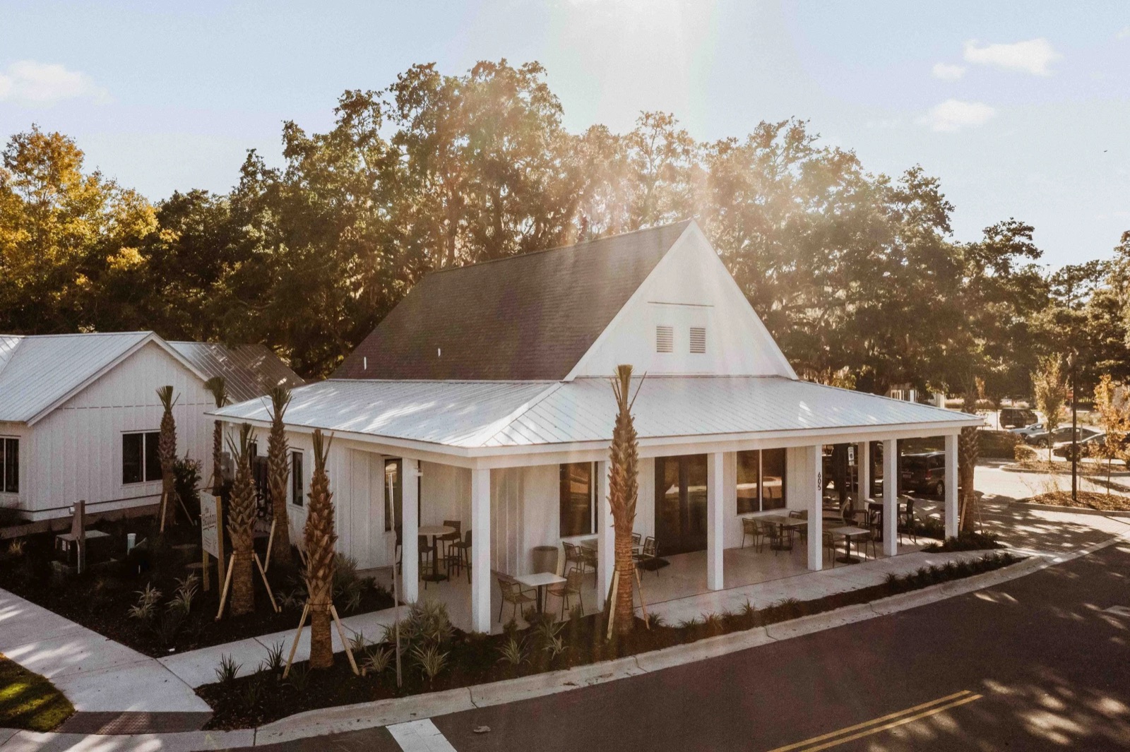 The Heyday at 605 Kindred Court in Hayes Park: a white café with a metal roof and a wraparound porch under live oaks